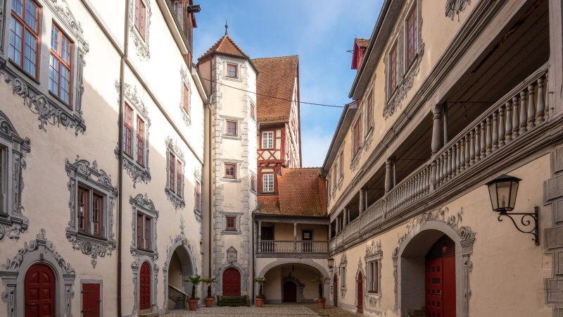 gepflasterter Schlossinnenhof, umgeben von hell verputzten Gebäuden mit grauer Illusionsmalerei umd Fenster und Türen, auf der rechten Bildseite eine offene Galerie im ersten Obergeschoss des Gebäudes, © Stadt Gaildorf gepflasterter Schlossinnenhof, umgeben von hell verputzten Gebäuden mit grauer Illusionsmalerei umd Fenster und Türen, auf der rechten Bildseite eine offene Galerie im ersten Obergeschoss des Gebäudes, © Stadt Gaildorf