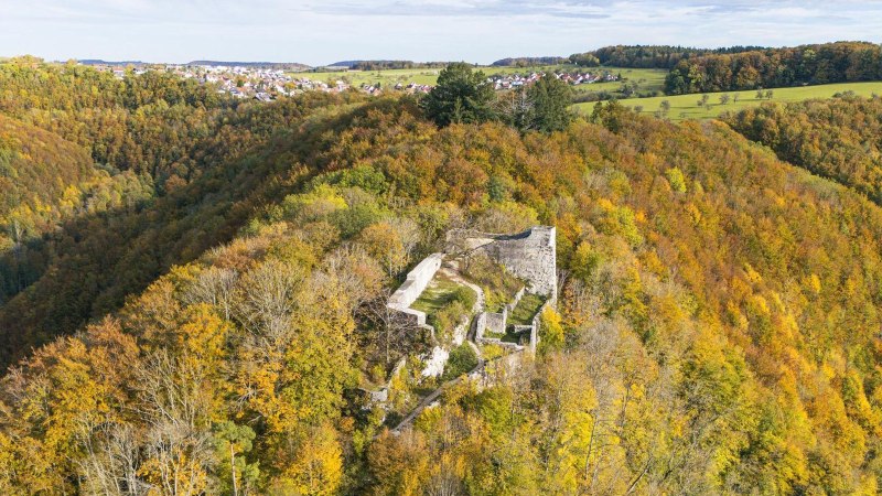 Luftaufnahme der Burgruine Hohenwittlingen, umgeben von herbstlich gefärbtem Wald. Im Hintergrund sind Felder und ein Dorf zu sehen., © Stuttgart-Marketing GmbH, Sarah Schmid Luftaufnahme der Burgruine Hohenwittlingen, umgeben von herbstlich gefärbtem Wald. Im Hintergrund sind Felder und ein Dorf zu sehen., © Stuttgart-Marketing GmbH, Sarah Schmid