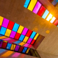 Bunte Glasfenster in einem modernen Gebäude werfen farbige Schatten auf die Wände. Sonnenlicht scheint durch die Fenster., © SMG, Achim Mende