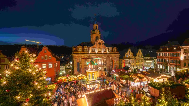 Beleuchtete Weihnachtspyramide und geschmückter Baum auf dem Weihnachtsmarkt in Schwäbisch Hall, umgeben von Menschen in festlicher Stimmung., © Michael Kühneisen