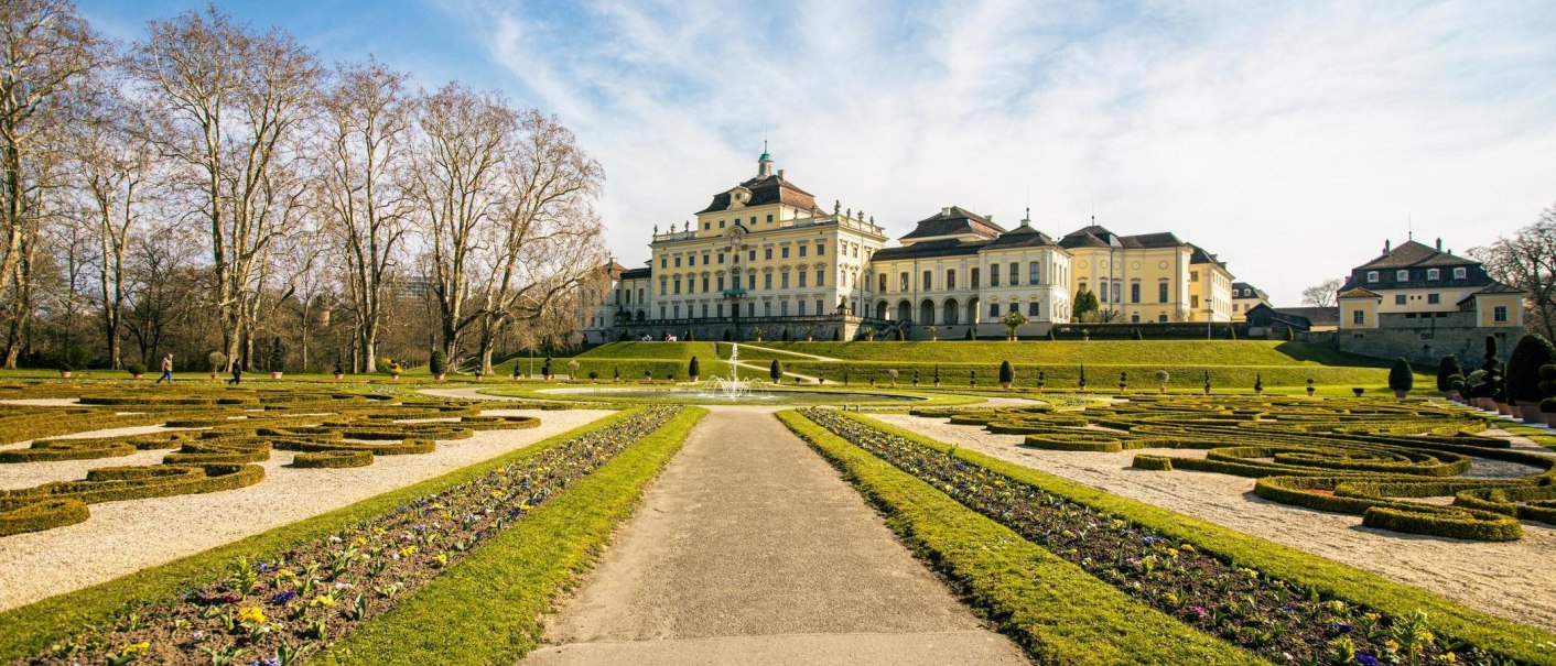 Das Schloss Ludwigsburg mit seinen prächtigen Gartenanlagen unter einem klaren blauen Himmel. Besucher spazieren durch die gepflegten Wege., © Stuttgart-Marketing GmbH, Sarah Schmid