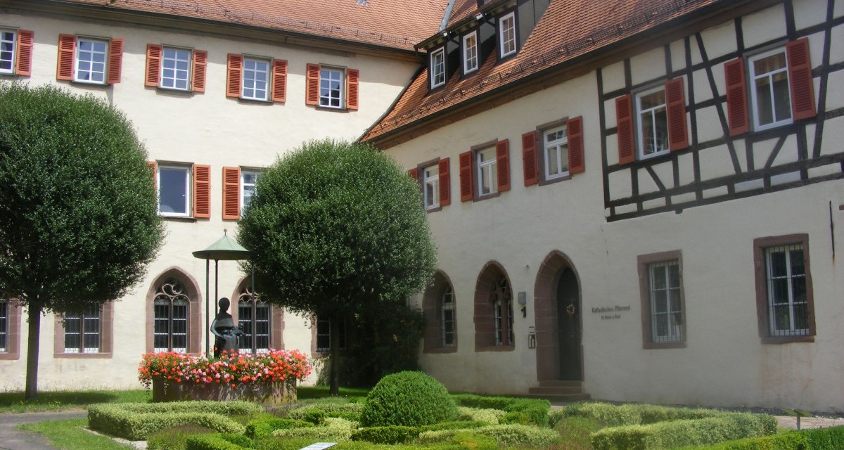 Historisches Gebäude mit Fachwerk und rotem Dach in Bad Mergentheim. Gepflegter Garten mit Brunnen und Blumen im Vordergrund., © Natur.Nah. Schönbuch & Heckengäu Historisches Gebäude mit Fachwerk und rotem Dach in Bad Mergentheim. Gepflegter Garten mit Brunnen und Blumen im Vordergrund., © Natur.Nah. Schönbuch & Heckengäu