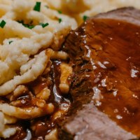 Ein Teller mit saftigem Braten in dunkler So&szlig;e, serviert mit Sp&auml;tzle, garniert mit Schnittlauch., &copy; SMG, Thomas Niederm&uuml;ller