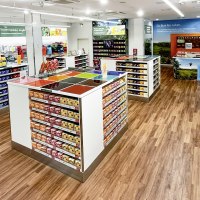 Ein heller Schokoshop mit bunten Ritter Sport Tafeln in Regalen, Holzboden und Werbepostern an den Wänden., © Alfred Ritter GmbH & Co. KG