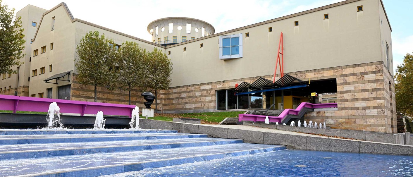 Das Haus der Geschichte zeigt moderne Architektur mit einem Brunnen im Vordergrund. Bäume säumen das Gebäude, das durch klare Linien und Farben besticht., © Haus der Geschichte Baden-Württemberg Das Haus der Geschichte zeigt moderne Architektur mit einem Brunnen im Vordergrund. Bäume säumen das Gebäude, das durch klare Linien und Farben besticht., © Haus der Geschichte Baden-Württemberg