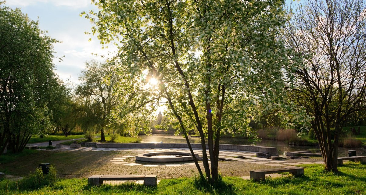 Ein Park mit blühenden Bäumen, Bänken und einem runden Brunnen. Die Sonne scheint durch die Blätter, und der Himmel ist leicht bewölkt., © Remstal Tourismus e.V. Ein Park mit blühenden Bäumen, Bänken und einem runden Brunnen. Die Sonne scheint durch die Blätter, und der Himmel ist leicht bewölkt., © Remstal Tourismus e.V.