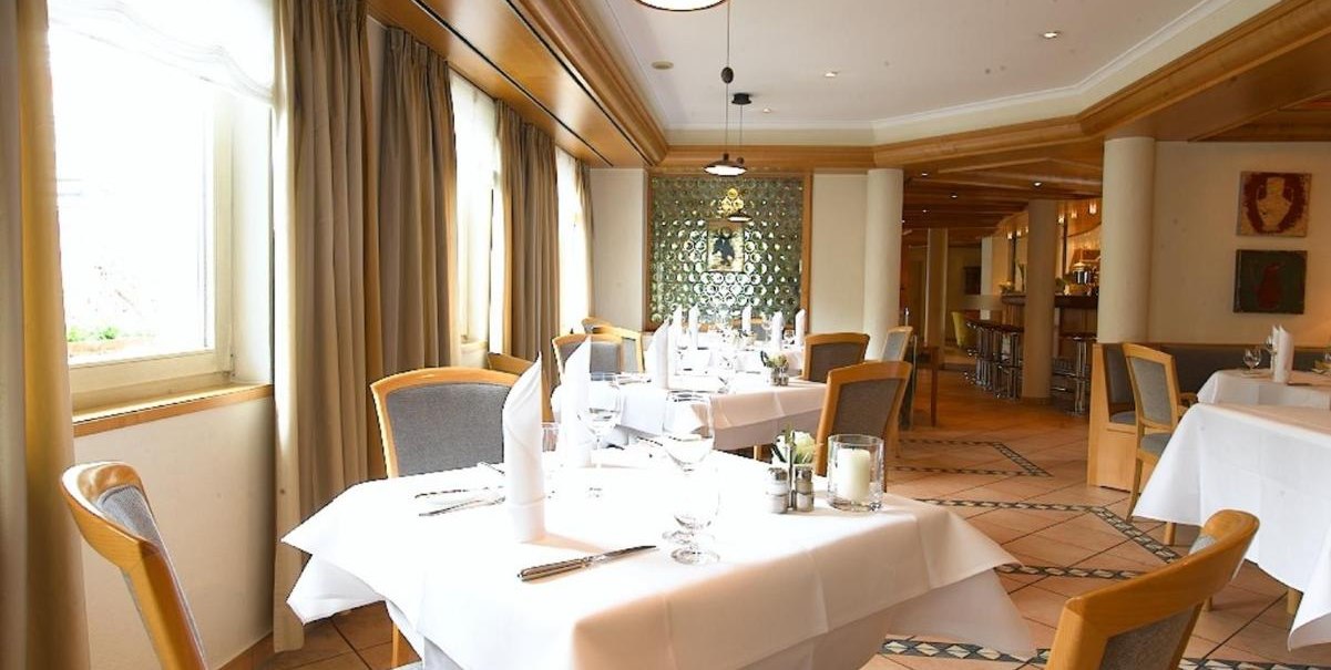 Ein elegantes Restaurant mit wei&szlig;en Tischdecken, Holzst&uuml;hlen und gro&szlig;en Fenstern. Die Einrichtung ist modern mit warmen Holzt&ouml;nen., &copy; Hotel am Park
