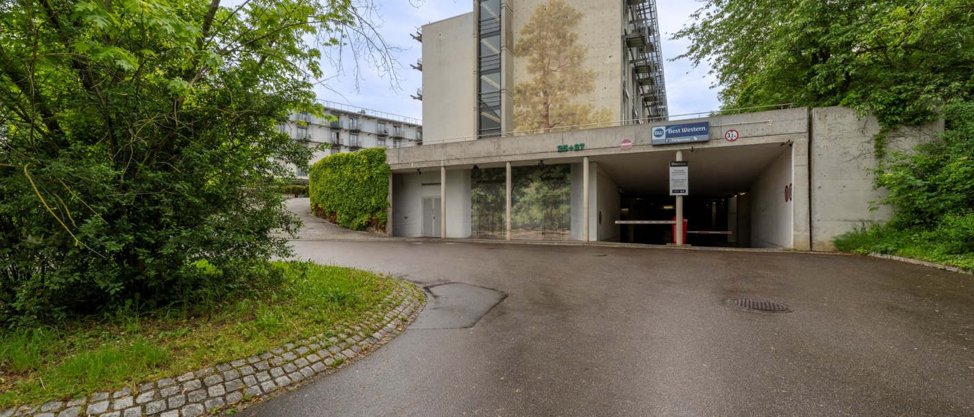 Einfahrt zu einer Tiefgarage mit Best Western Schild. Die Umgebung ist grün mit Bäumen und Pflanzen. Der Boden ist asphaltiert., © Plaza Residence Stuttgart-Ditzingen Einfahrt zu einer Tiefgarage mit Best Western Schild. Die Umgebung ist grün mit Bäumen und Pflanzen. Der Boden ist asphaltiert., © Plaza Residence Stuttgart-Ditzingen