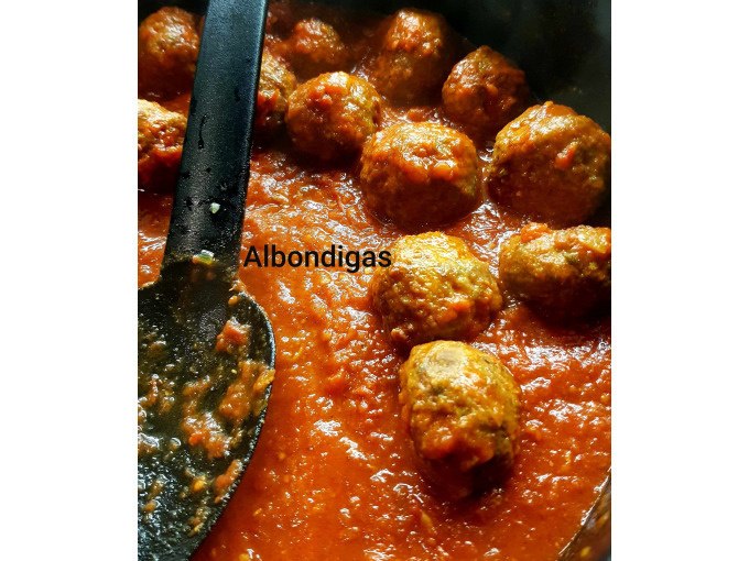 Fleischbällchen in Tomatensauce, bezeichnet als 'Albondigas', mit einem schwarzen Kochlöffel in einer Pfanne., © Kultweine-Kochwelten-Kunstücke - Kochschule Sonja Lenz Fleischbällchen in Tomatensauce, bezeichnet als 'Albondigas', mit einem schwarzen Kochlöffel in einer Pfanne., © Kultweine-Kochwelten-Kunstücke - Kochschule Sonja Lenz