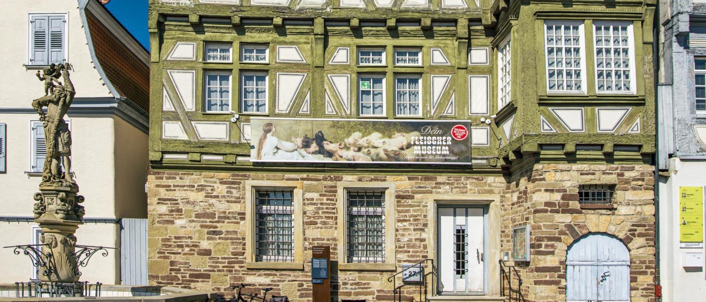 Fachwerkhaus mit Werbeschild f&uuml;r ein Museum. Links eine Brunnenstatue. Das Geb&auml;ude hat gr&uuml;ne und wei&szlig;e Details, die Fassade ist aus Stein., &copy; Stuttgart-Marketing GmbH, Sarah Schmid