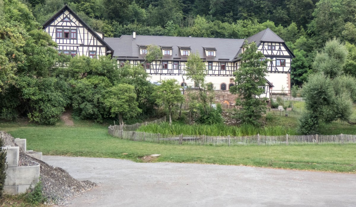 Ein gro&szlig;es Fachwerkhaus steht inmitten von B&auml;umen und gr&uuml;ner Landschaft. Ein Weg f&uuml;hrt an einer Wiese vorbei zum Haus., &copy; Natur.Nah. Sch&ouml;nbuch & Heckeng&auml;u