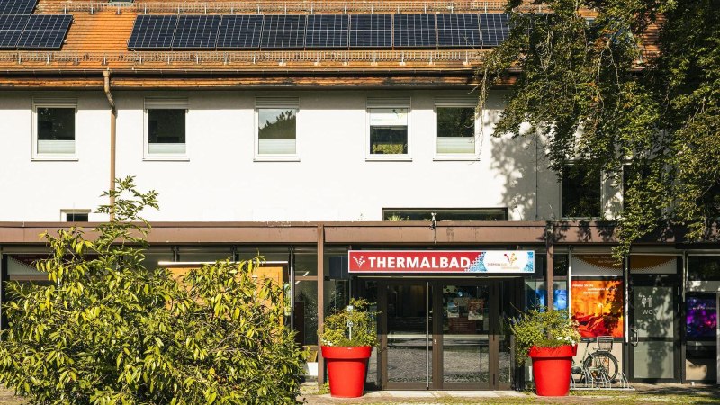 Eingang des Thermalbads in Bad Überkingen, umgeben von Pflanzen. Auf dem Dach sind Solarpanele installiert. Ein roter Blumentopf steht vor dem Eingang., © Stuttgart-Marketing GmbH, Sarah Schmid Eingang des Thermalbads in Bad Überkingen, umgeben von Pflanzen. Auf dem Dach sind Solarpanele installiert. Ein roter Blumentopf steht vor dem Eingang., © Stuttgart-Marketing GmbH, Sarah Schmid