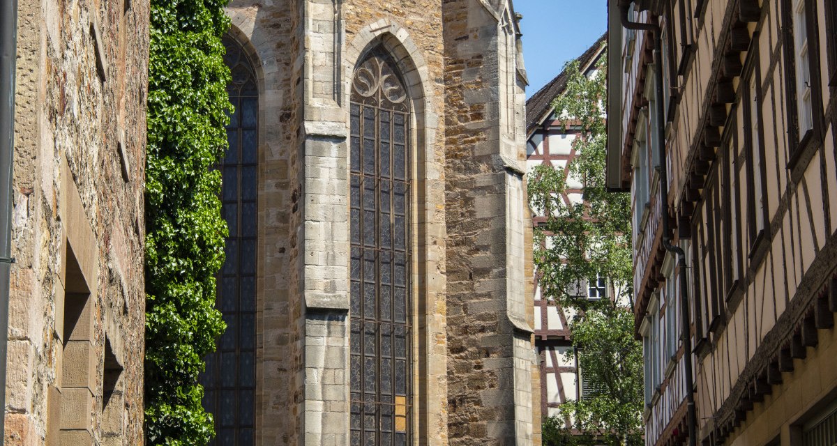 Gotische Martinskirche mit hohen Fenstern, umgeben von Fachwerkhäusern und einem Straßenschild im Vordergrund. Sonniger Tag, blauer Himmel., © Stadt Kirchheim unter Teck Gotische Martinskirche mit hohen Fenstern, umgeben von Fachwerkhäusern und einem Straßenschild im Vordergrund. Sonniger Tag, blauer Himmel., © Stadt Kirchheim unter Teck