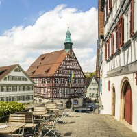 Blick auf historische Fachwerkhäuser in Backnang. Im Vordergrund leere Sitzplätze, im Hintergrund ein blauer Himmel mit Wolken., © SMG, Sarah Schmid Blick auf historische Fachwerkhäuser in Backnang. Im Vordergrund leere Sitzplätze, im Hintergrund ein blauer Himmel mit Wolken., © SMG, Sarah Schmid