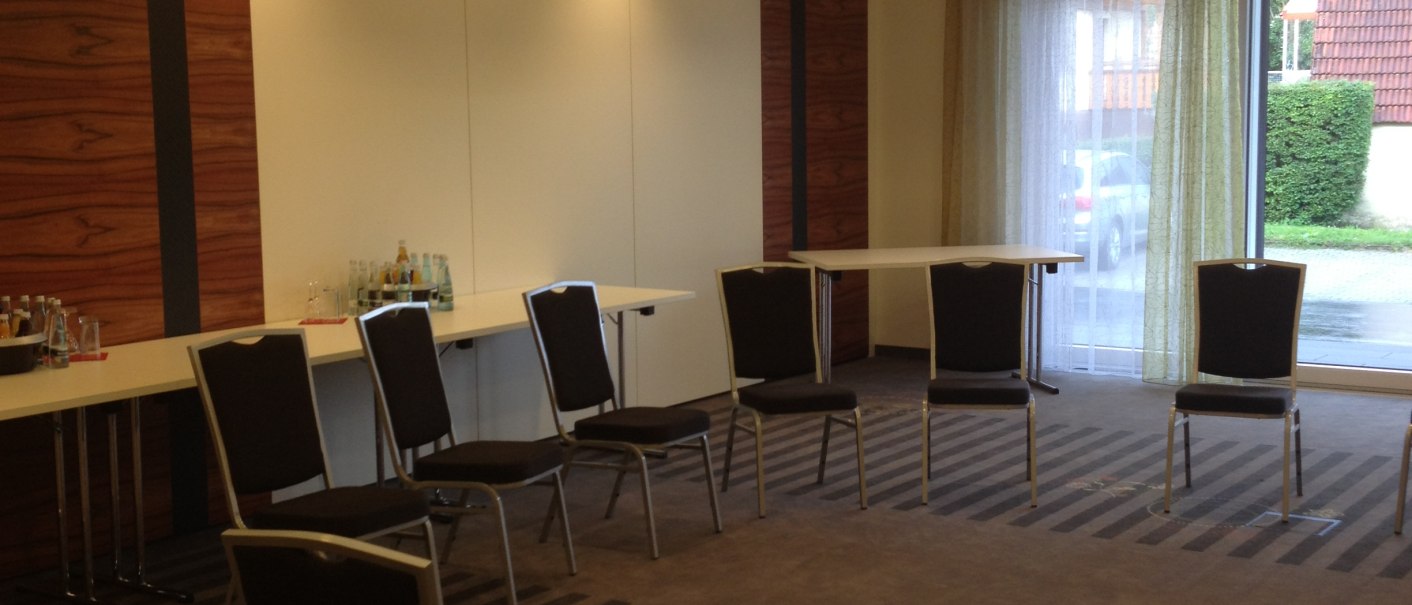 Ein leerer Tagungsraum mit Stühlen im Kreis und Tischen an der Wand. Die Beleuchtung ist warm, und ein Kronleuchter hängt von der Decke., © Hotel & Restaurant Sonne