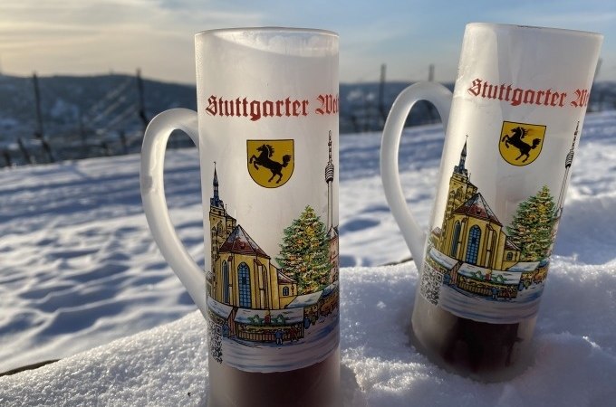 Zwei Gl&uuml;hweintassen mit Stuttgart-Motiv stehen im Schnee. Im Hintergrund sind Weinberge und ein blauer Himmel zu sehen., &copy; Weingenuss Stuttgart