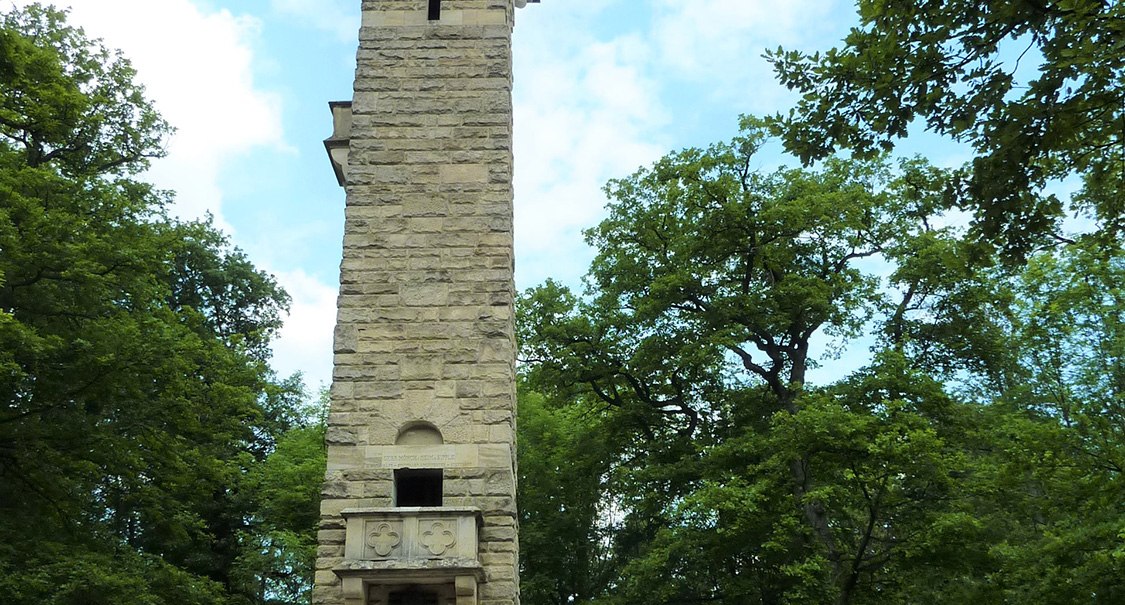 Der Kernenturm erhebt sich steinern inmitten eines Waldes. Eine Person geht im Vordergrund. Der Himmel ist leicht bewölkt., © Ingrid Sachsenmaier