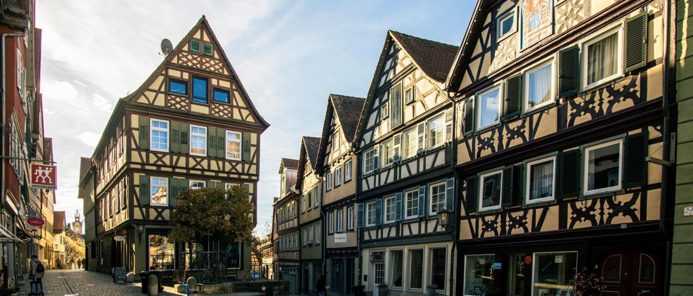 Fachwerkhäuser in der Altstadt von Schwäbisch Hall, beleuchtet von der Sonne. Die Straße ist gepflastert und von historischen Gebäuden gesäumt., © Stuttgart-Marketing GmbH, Sarah Schmid Fachwerkhäuser in der Altstadt von Schwäbisch Hall, beleuchtet von der Sonne. Die Straße ist gepflastert und von historischen Gebäuden gesäumt., © Stuttgart-Marketing GmbH, Sarah Schmid