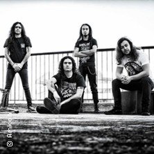 Vier Männer in schwarzer Kleidung posieren auf einem Dach, zwei stehen, zwei sitzen. Schwarz-Weiß-Foto mit urbanem Hintergrund., © links im Bild