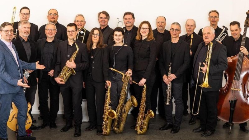 Eine Bigband in schwarzer Kleidung posiert mit Instrumenten wie Saxophonen, Trompeten und einem Kontrabass vor einem wei&szlig;en Hintergrund., &copy; Kulturzentrum Dieselstrasse