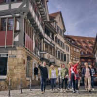 Eine Gruppe von Menschen spaziert durch eine Altstadt mit Fachwerkhäusern. Sie wirken fröhlich und interessiert., © Esslinger Stadtmarketing &amp; Tourismus GmbH