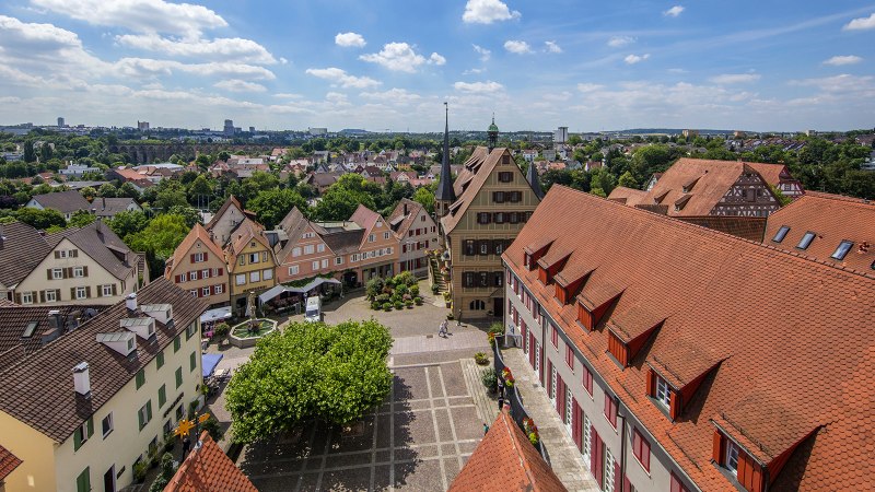 Panoramablick auf Bietigheim-Bissingen mit Fachwerkhäusern, roten Ziegeldächern und einem zentralen Platz, umgeben von grüner Landschaft und blauem Himmel., © SMG, Achim Mende Panoramablick auf Bietigheim-Bissingen mit Fachwerkhäusern, roten Ziegeldächern und einem zentralen Platz, umgeben von grüner Landschaft und blauem Himmel., © SMG, Achim Mende