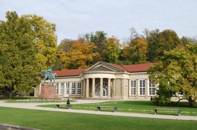 Historisches Gebäude im Kurpark Bad Cannstatt mit Reiterstatue und herbstlicher Baumkulisse., © Cool-Tours StattReisen