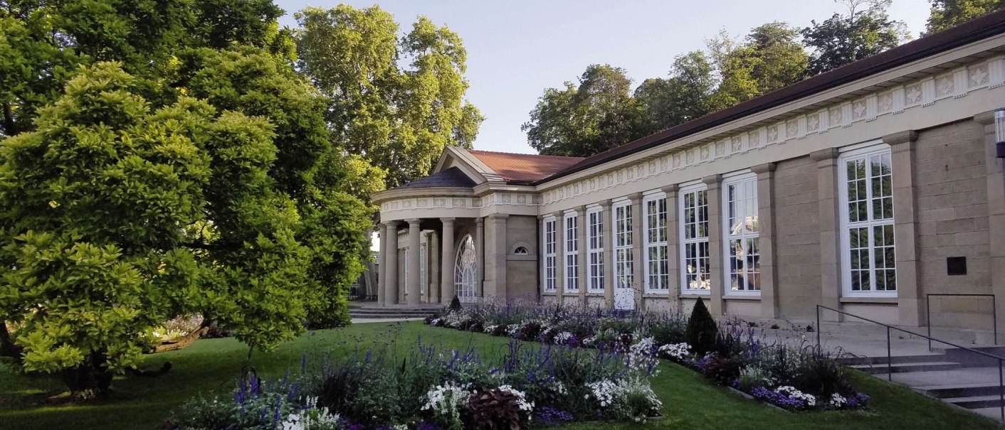 Der Kursaal Bad Cannstatt mit klassischer Architektur, großen Fenstern und einem gepflegten Garten im Vordergrund, umgeben von Bäumen., © Stuttgart-Marketing GmbH Der Kursaal Bad Cannstatt mit klassischer Architektur, großen Fenstern und einem gepflegten Garten im Vordergrund, umgeben von Bäumen., © Stuttgart-Marketing GmbH