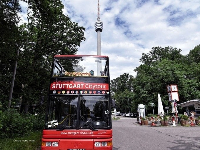 Roter Doppeldeckerbus der Stuttgart Citytour vor dem Stuttgarter Fernsehturm, umgeben von Bäumen und einem Café., © SMG, Pierre Polak Roter Doppeldeckerbus der Stuttgart Citytour vor dem Stuttgarter Fernsehturm, umgeben von Bäumen und einem Café., © SMG, Pierre Polak