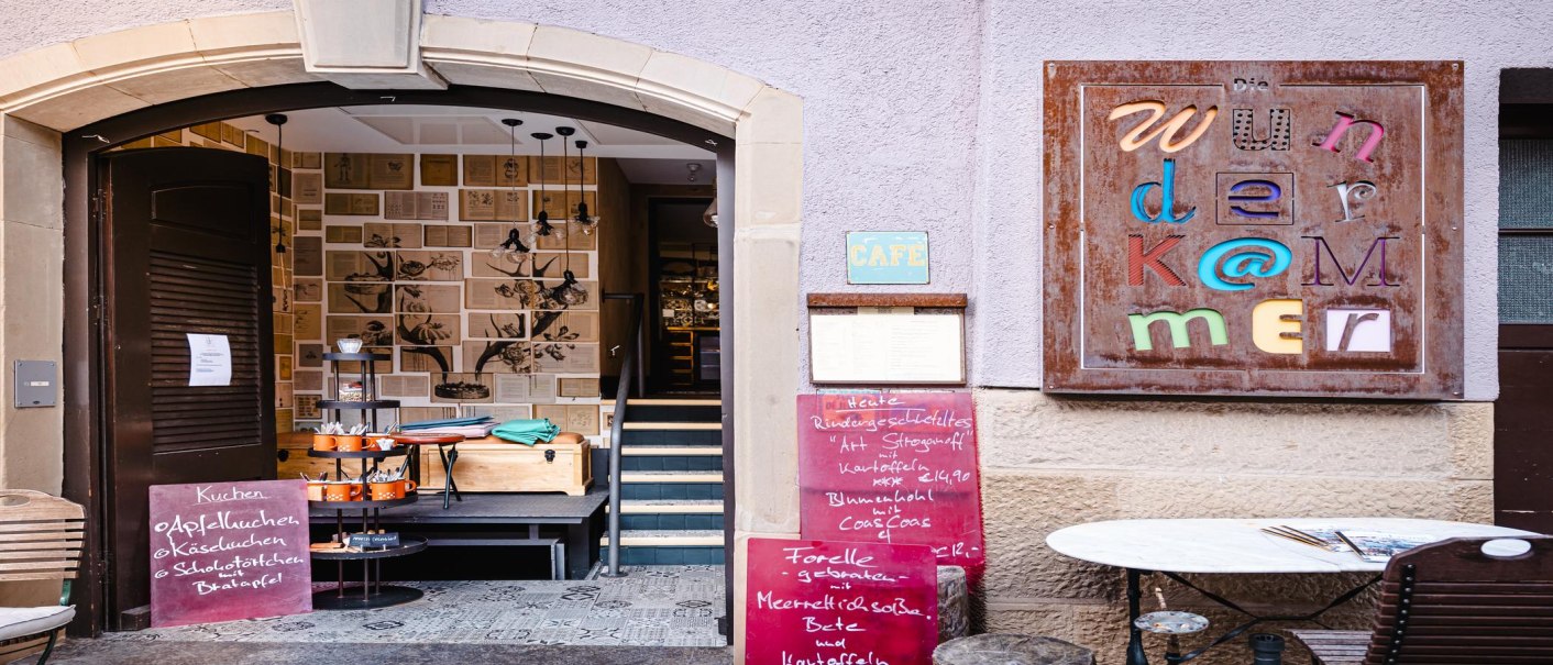 Eingang zur Wunderkammer mit dekorativen W&auml;nden, buntem Schild und Speisekarten. Einladende Atmosph&auml;re mit Caf&eacute;-Charme., &copy; by Canto