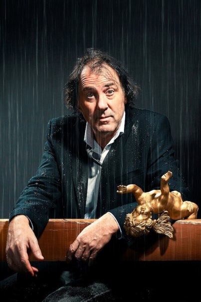 Ein Mann in einem nassen Anzug steht unter Regen, mit einem goldenen Engel auf einem Tisch vor ihm., © Veranstaltungsring Metzingen e.V. Ein Mann in einem nassen Anzug steht unter Regen, mit einem goldenen Engel auf einem Tisch vor ihm., © Veranstaltungsring Metzingen e.V.