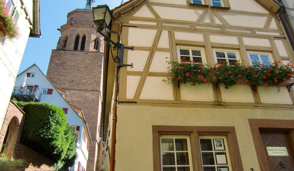 Fachwerkhaus mit blühendem Blumenkasten, daneben ein Kirchturm. Treppen führen zwischen den Gebäuden hinauf. Klarer blauer Himmel im Hintergrund., © Natur.Nah. Schönbuch & Heckengäu Fachwerkhaus mit blühendem Blumenkasten, daneben ein Kirchturm. Treppen führen zwischen den Gebäuden hinauf. Klarer blauer Himmel im Hintergrund., © Natur.Nah. Schönbuch & Heckengäu