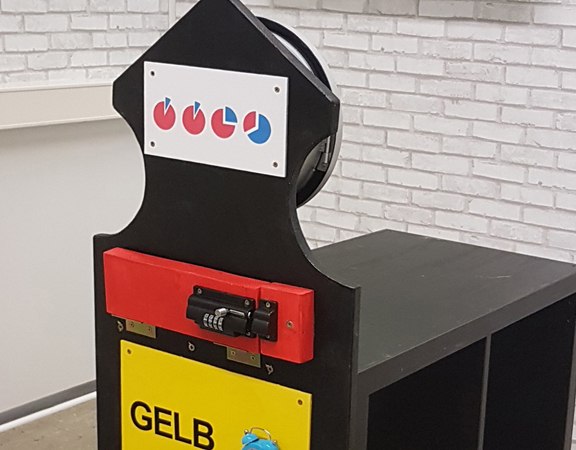 Escape-Room-Puzzle mit farbigen Schubladen und Symbolen. An der Wand eine grüne Dekoration mit Uhr und Rätseln., © Flucht-Raum Escape-Room-Puzzle mit farbigen Schubladen und Symbolen. An der Wand eine grüne Dekoration mit Uhr und Rätseln., © Flucht-Raum