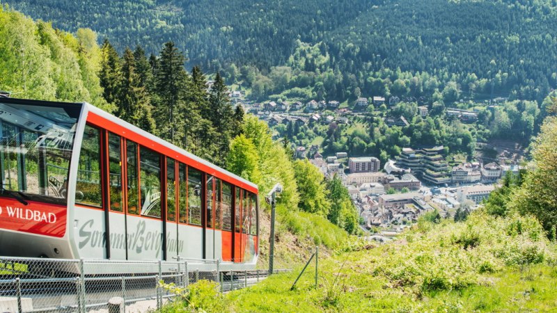 Die Sommerbergbahn in Bad Wildbad f&auml;hrt durch gr&uuml;ne H&auml;nge mit Blick auf den Ort im Tal und dichte W&auml;lder., &copy; Touristik Bad Wildbad Gmbh