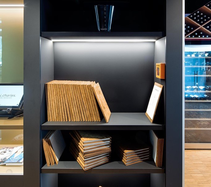 Ein Regal mit Champagnerflaschen oben und gestapelten Speisekarten darunter in einem modernen Restaurantambiente., © Hotel am Remspark Ein Regal mit Champagnerflaschen oben und gestapelten Speisekarten darunter in einem modernen Restaurantambiente., © Hotel am Remspark