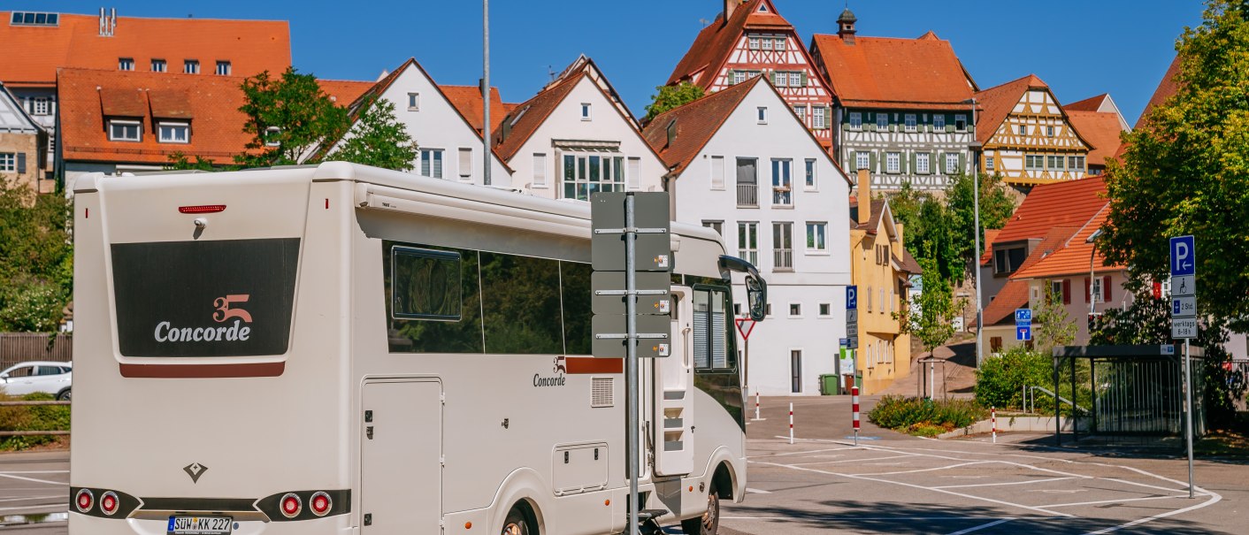 Wohnmobil auf einem Parkplatz in Bietigheim-Bissingen, umgeben von historischen Fachwerkhäusern und blauem Himmel., © SMG, Thomas Niedermüller Wohnmobil auf einem Parkplatz in Bietigheim-Bissingen, umgeben von historischen Fachwerkhäusern und blauem Himmel., © SMG, Thomas Niedermüller