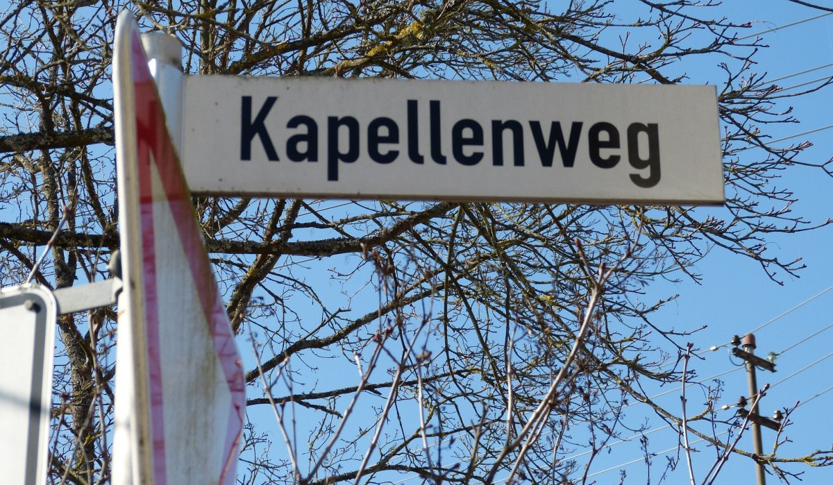 Ein Straßenschild mit der Aufschrift 'Kapellenweg' vor einem kahlen Baum und blauem Himmel., © Natur.Nah. Schönbuch & Heckengäu