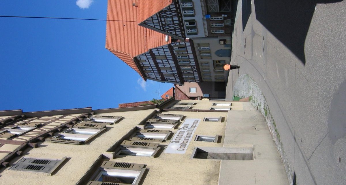 Straßenszene mit Fachwerkhäusern, blauer Himmel und einem Schild an der Hauswand. Eine Person in orangefarbener Kleidung geht die Straße entlang., © Land der 1000 Hügel - Kraichgau-Stromberg Straßenszene mit Fachwerkhäusern, blauer Himmel und einem Schild an der Hauswand. Eine Person in orangefarbener Kleidung geht die Straße entlang., © Land der 1000 Hügel - Kraichgau-Stromberg