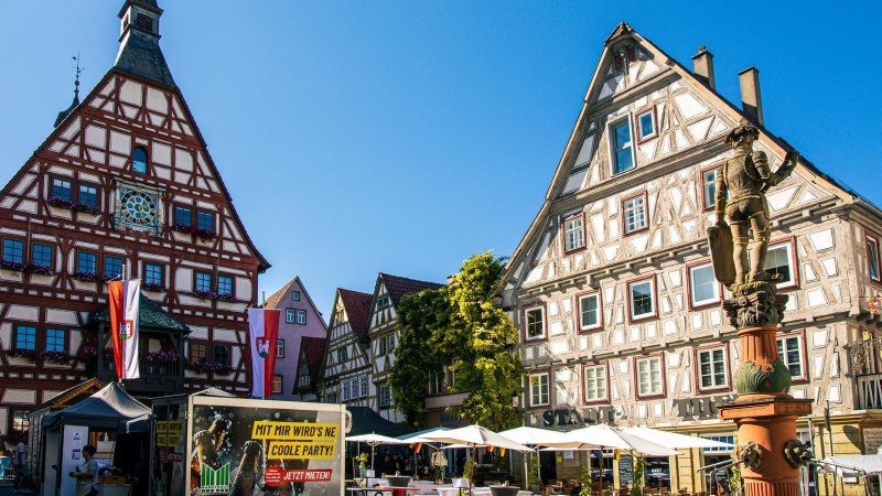 Das historische Fachwerk-Rathaus von Besigheim am Marktplatz, umgeben von Fachwerkhäusern und einem Brunnen, bei strahlend blauem Himmel., © Stuttgart-Marketing GmbH, Sarah Schmid Das historische Fachwerk-Rathaus von Besigheim am Marktplatz, umgeben von Fachwerkhäusern und einem Brunnen, bei strahlend blauem Himmel., © Stuttgart-Marketing GmbH, Sarah Schmid