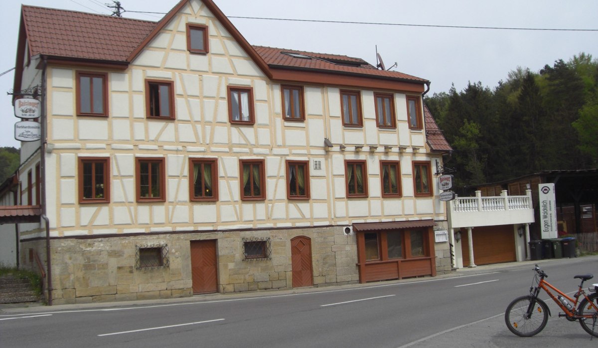 Fachwerkhaus mit mehreren Fenstern an einer Straße, Fahrrad im Vordergrund. Wald im Hintergrund., © Natur.Nah. Schönbuch & Heckengäu