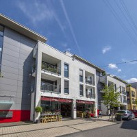 Moderne Wohngebäude in Fellbach, sonniger Tag, blauer Himmel, Autos parken entlang der Straße, Menschen spazieren., © Stadt Fellbach