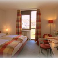 Gemütliches Doppelzimmer mit zwei Betten, Schreibtisch, Fernseher und Fenster mit gestreiften Vorhängen. Helle, einladende Atmosphäre., © Hotel Körschtal