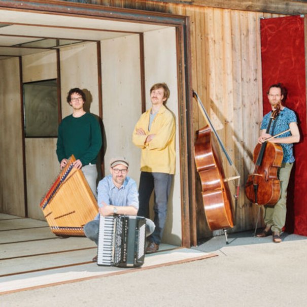 Vier Musiker posieren mit ihren Instrumenten, darunter ein Akkordeon, ein Kontrabass und ein Cello, vor einer Holzwand., © Konzertkreis Triangel Compagnia Compostelli e.V. Vier Musiker posieren mit ihren Instrumenten, darunter ein Akkordeon, ein Kontrabass und ein Cello, vor einer Holzwand., © Konzertkreis Triangel Compagnia Compostelli e.V.