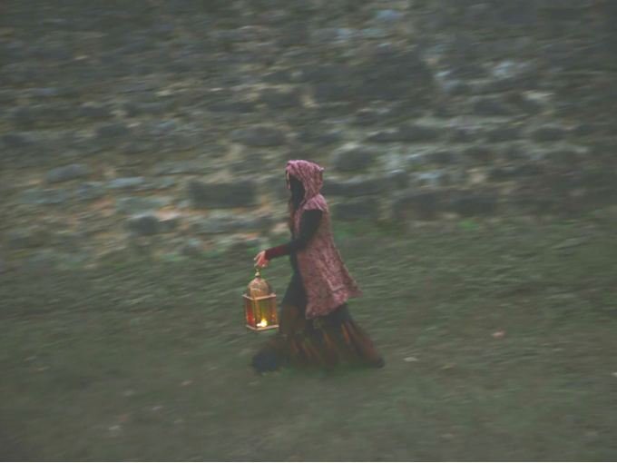 Eine Person in einem Kapuzenmantel trägt eine leuchtende Laterne vor einer alten Steinmauer entlang., © Esslinger Stadtmarketing &amp; Tourismus GmbH