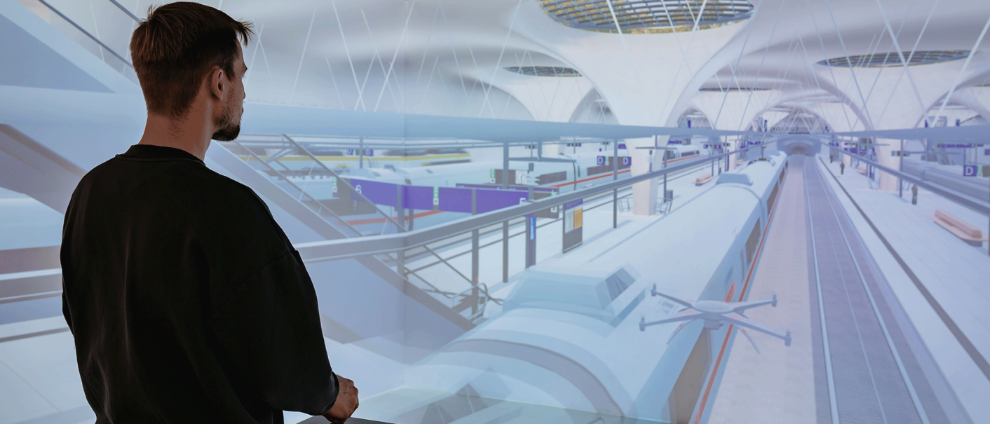 Ein Mann steht vor einer virtuellen Projektion eines futuristischen Bahnhofs mit Zügen und Bahnsteigen., © Thomas Niedermüller