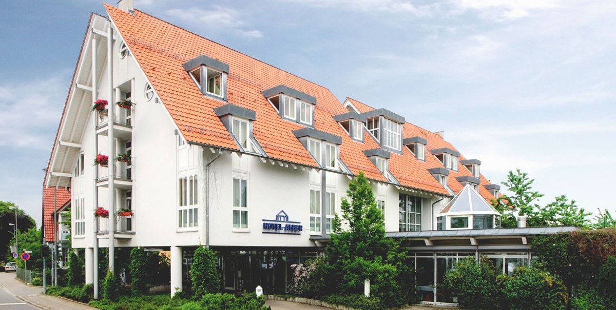 Modernes Hotel mit roten Ziegeldächern und weißen Wänden, umgeben von Bäumen und Pflanzen, an einer Straße gelegen., © Hotel Alber KG Modernes Hotel mit roten Ziegeldächern und weißen Wänden, umgeben von Bäumen und Pflanzen, an einer Straße gelegen., © Hotel Alber KG