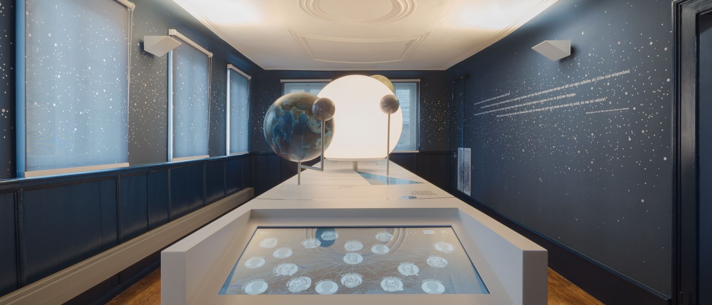 Der Keplerraum im Stadtmuseum Leonberg zeigt interaktive Displays und Planetenmodelle in einem dunkelblauen Raum mit Sternenmuster., © Brigida Gonzalez