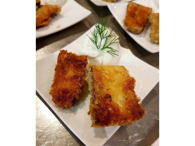 Zwei frittierte, panierte Stücke auf einem Teller mit weißer Sauce und Dillgarnitur., © Kultweine-Kochwelten-Kunstücke - Kochschule Sonja Lenz Zwei frittierte, panierte Stücke auf einem Teller mit weißer Sauce und Dillgarnitur., © Kultweine-Kochwelten-Kunstücke - Kochschule Sonja Lenz