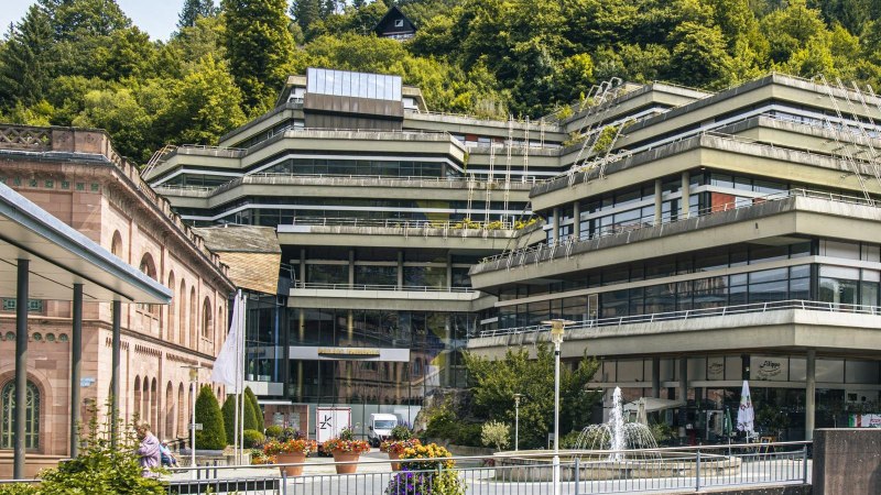 Modernes Gebäude mit Terrassen und Glasfronten, umgeben von Bäumen. Im Vordergrund Blumen und ein Brunnen., © Stuttgart-Marketing GmbH, Sarah Schmid