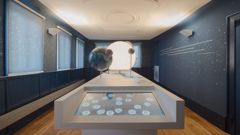 Der Keplerraum im Stadtmuseum Leonberg zeigt interaktive Displays und Planetenmodelle in einem dunkelblauen Raum mit Sternenmuster., © Brigida Gonzalez Der Keplerraum im Stadtmuseum Leonberg zeigt interaktive Displays und Planetenmodelle in einem dunkelblauen Raum mit Sternenmuster., © Brigida Gonzalez